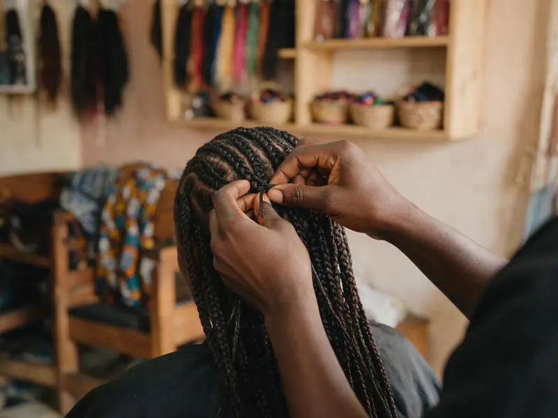 Mains d'une coiffeuse réalisant des tresses